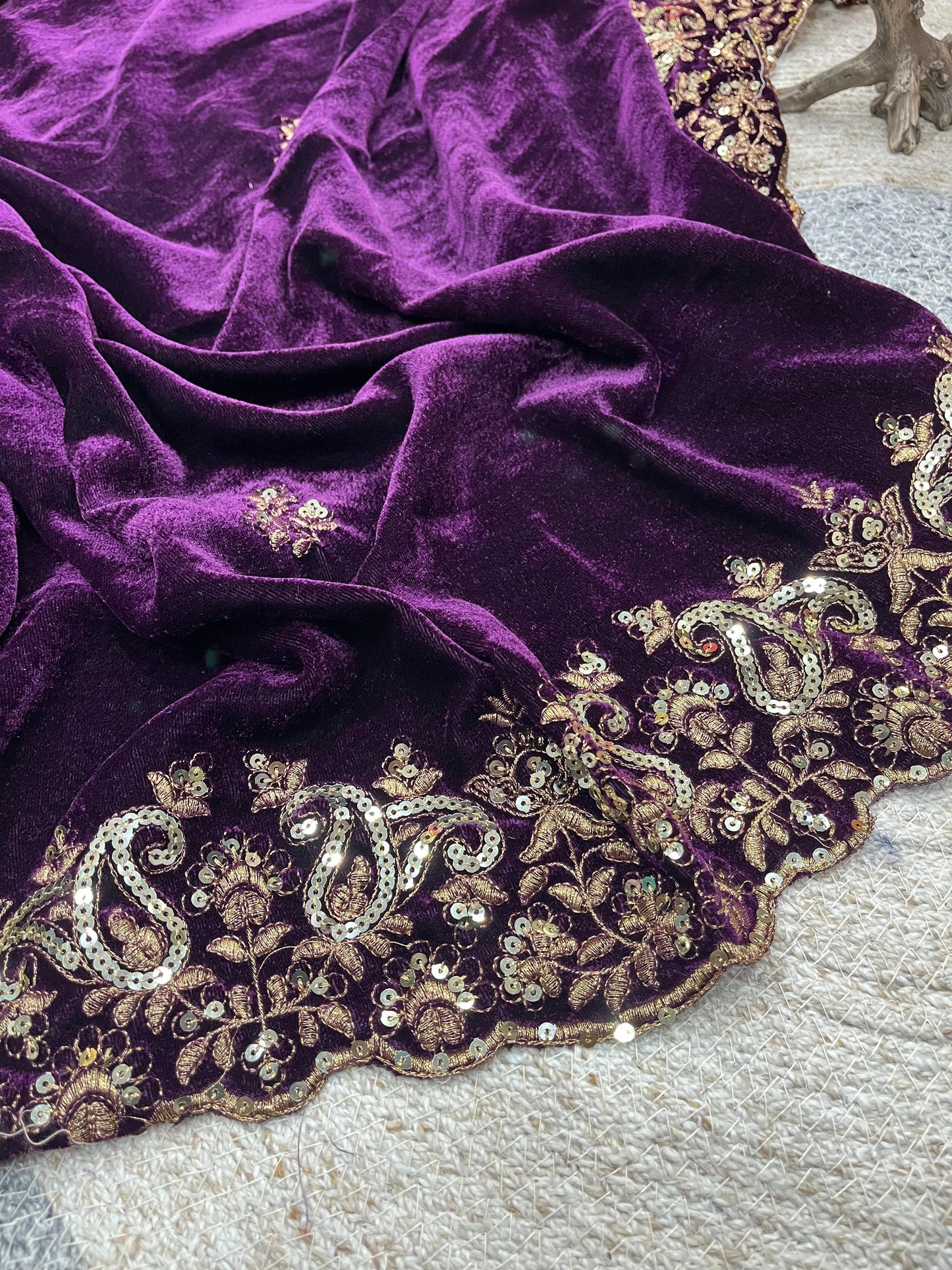 Purple fabric with intricate gold embroidery on a textured surface