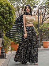 Woman in a traditional outfit with a black and gold patterned saree in an outdoor setting.