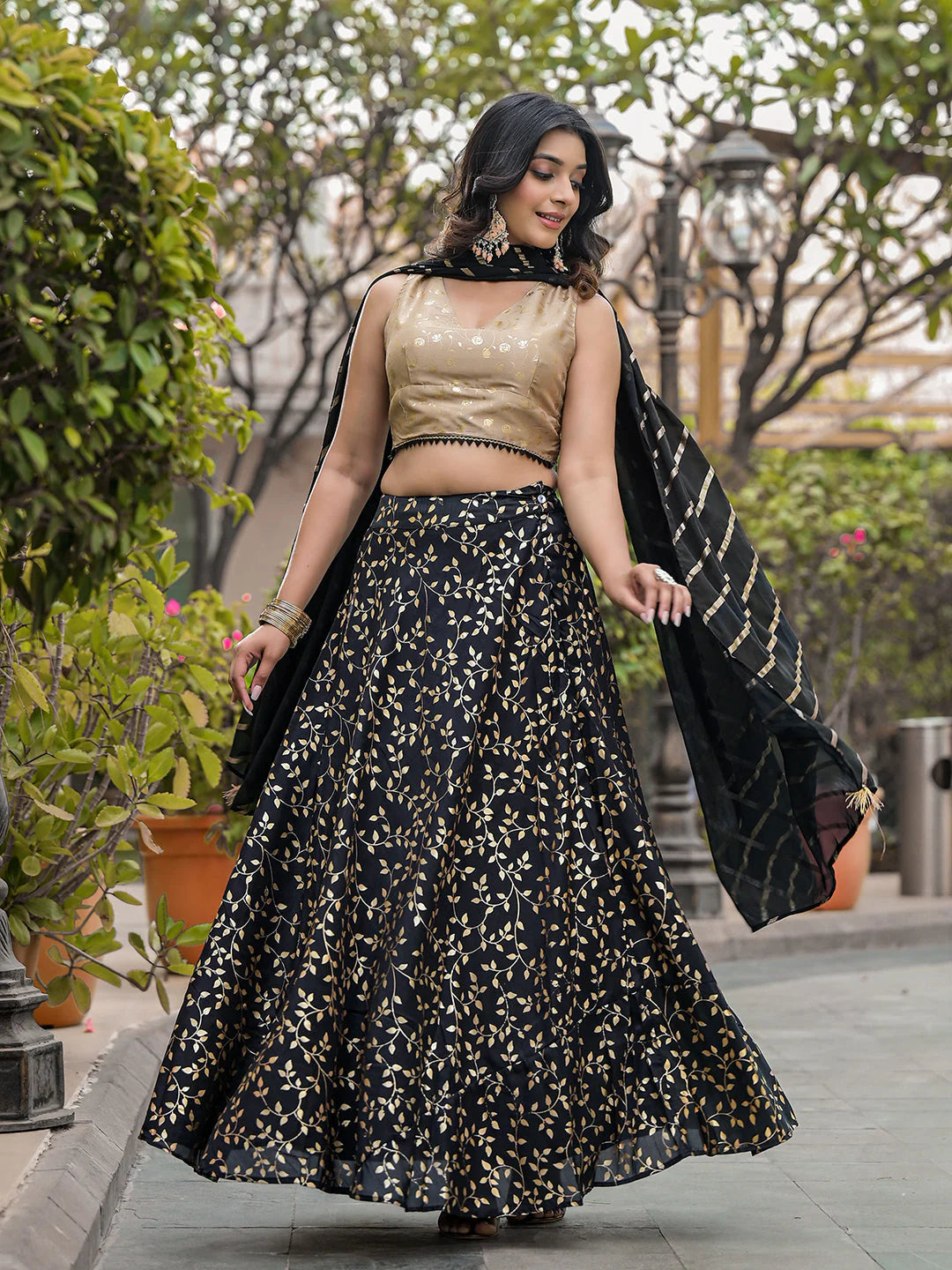 Woman in a black and gold traditional outfit walking outdoors.