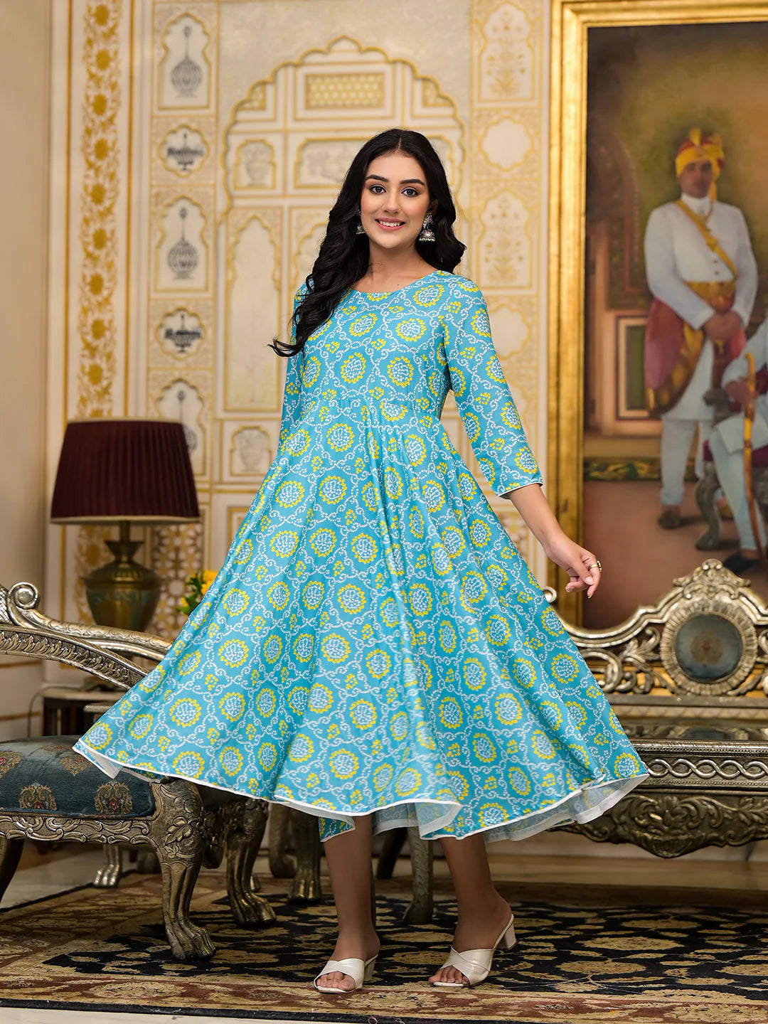 Woman in a blue patterned dress standing in an ornate room with decorative walls and furniture.